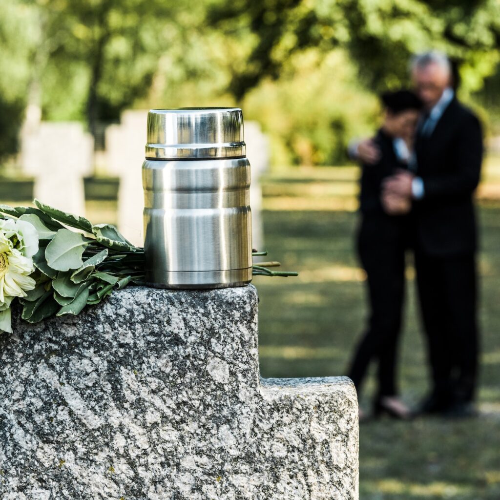 selective focus of white flowers and cemetery urn on tombstone