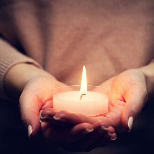 Candle light glowing in woman's hands. Praying, faith, religion