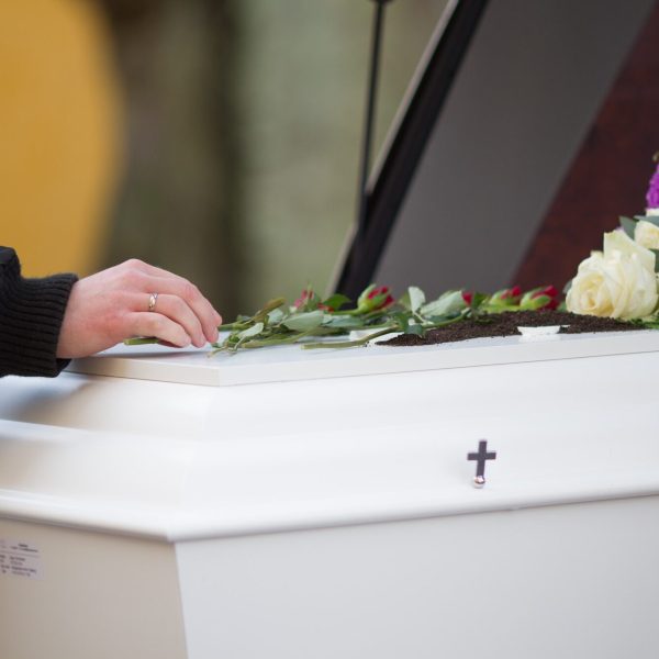 Closeup shot of a person hand on a casket with a blurred background