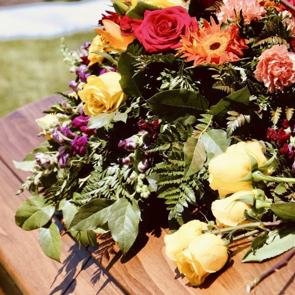 Lovely floral arrangement on wood casket.