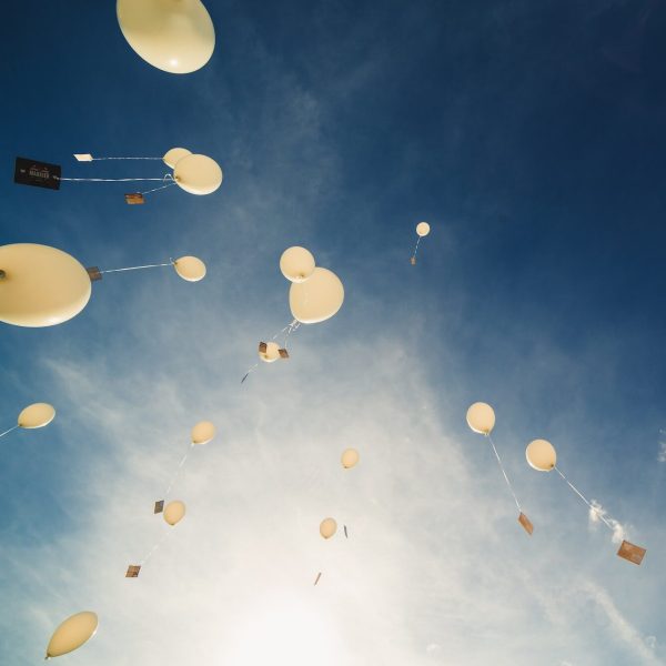 White balloons fly up into the blue sky. The release of festive balloons in the clouds. Celebration