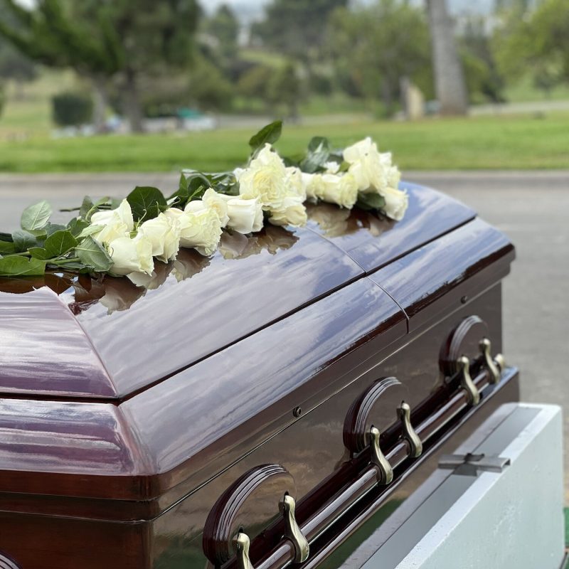 white roses on a mahogany casket